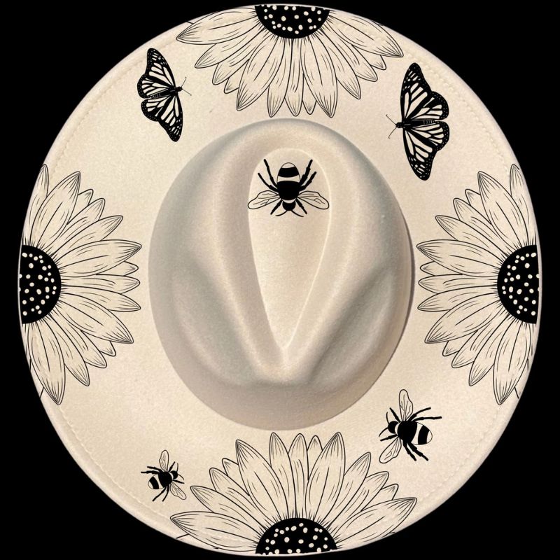 A white wide brim hat with a floral pattern featuring sunflowers and butterflies, and a bee motif at the top.