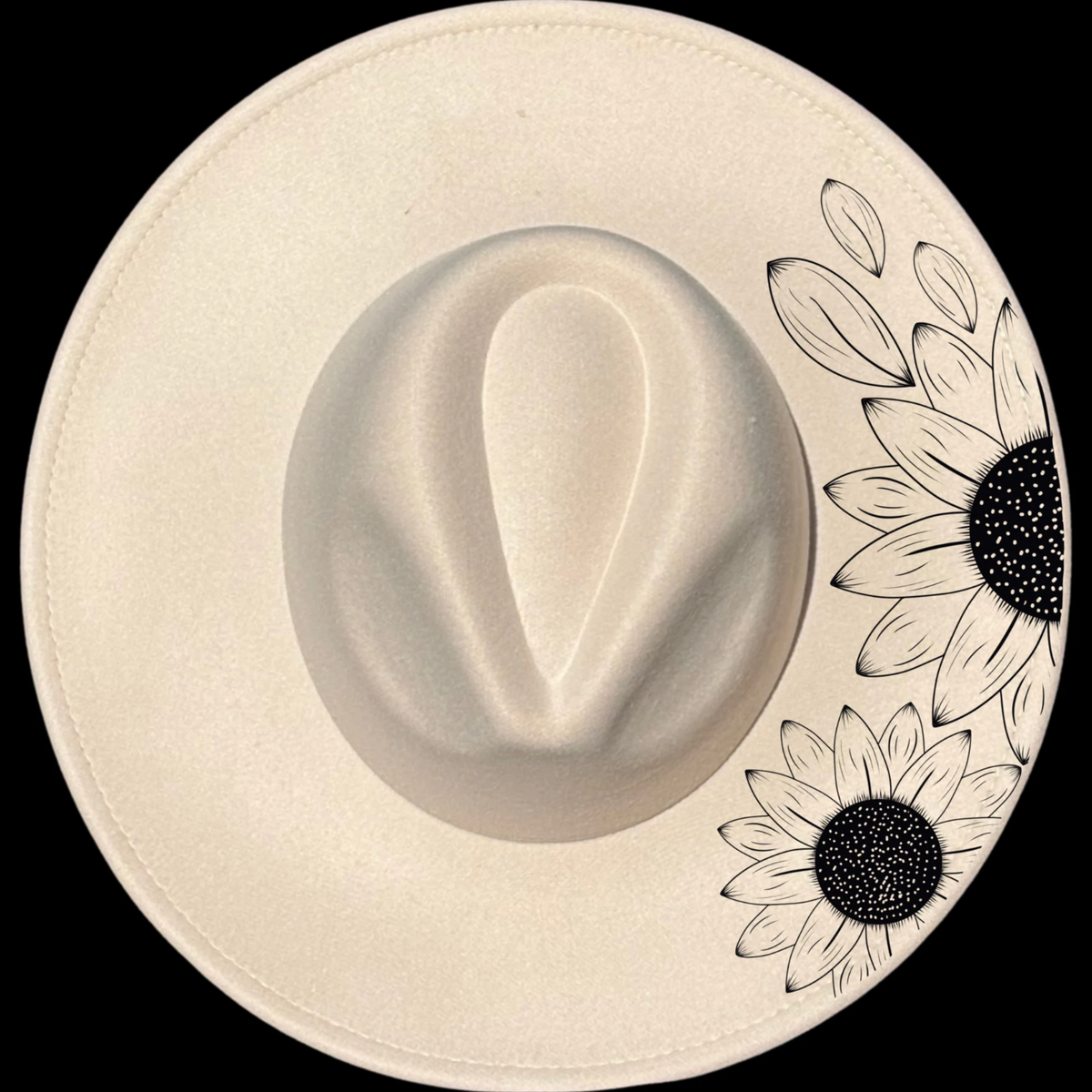 A beige wide brim hat with a burning design that resembles a sunflower, and additional floral designs as a border.