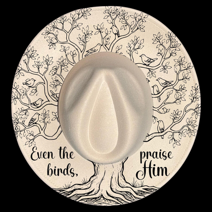A wide brim hat with a tree of life illustration, featuring text 'Even the birds praise Him' on a black background.