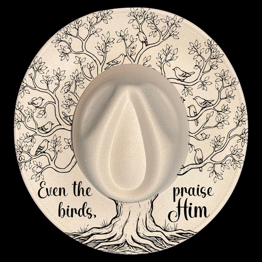 A wide brim hat with a tree of life illustration, featuring text 'Even the birds praise Him' on a black background.