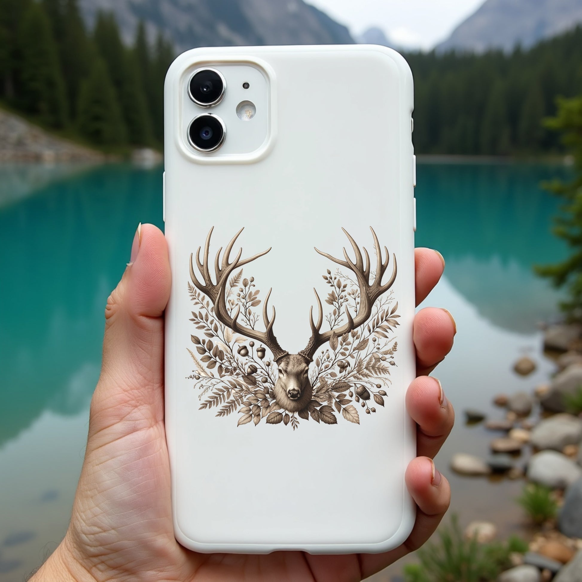 Phone case with deer design held in front of a scenic lake and mountains