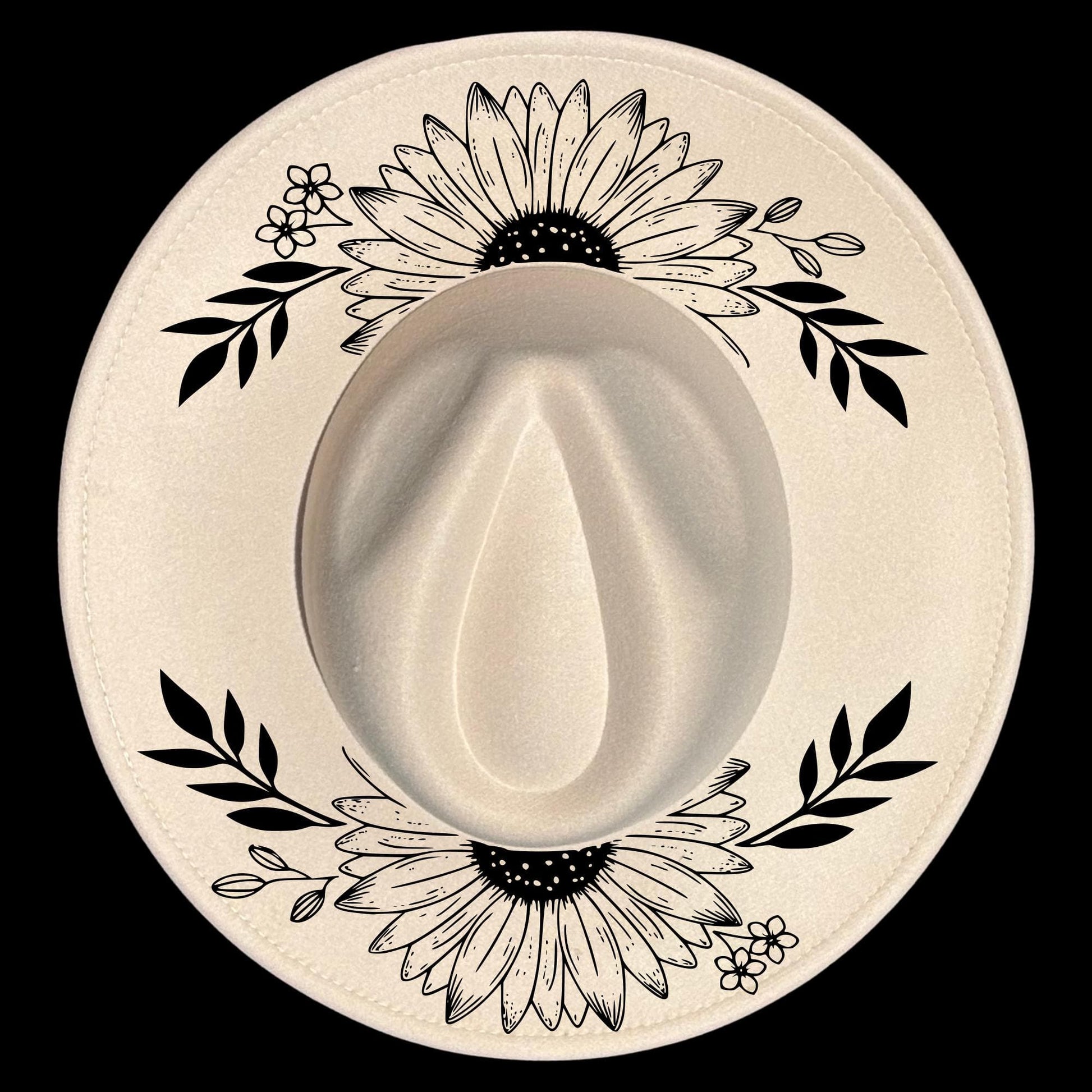 A wide brim hat with black floral and leaf patterns on a white background