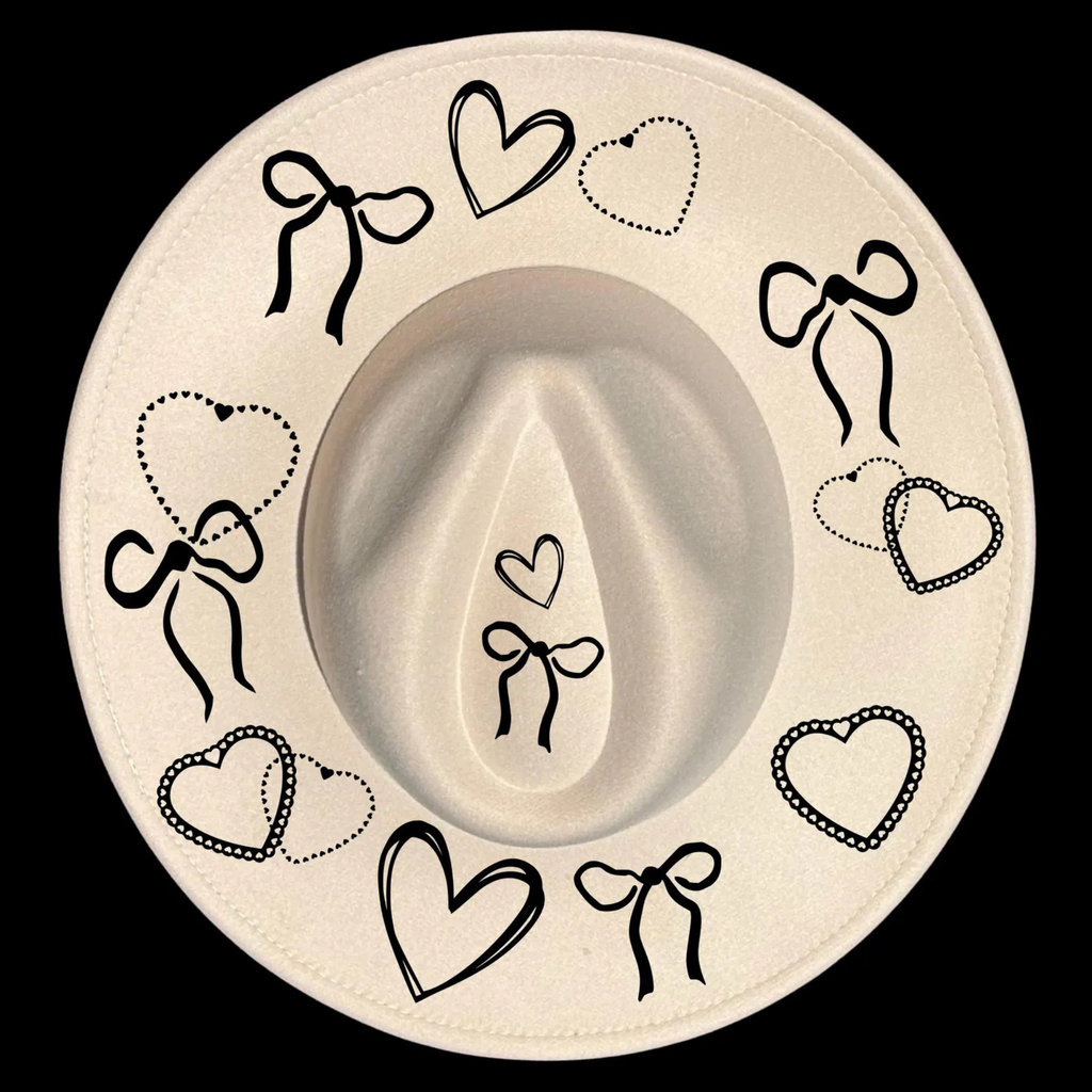 A wide brim cowboy hat with black decorative bows and hearts on a black background