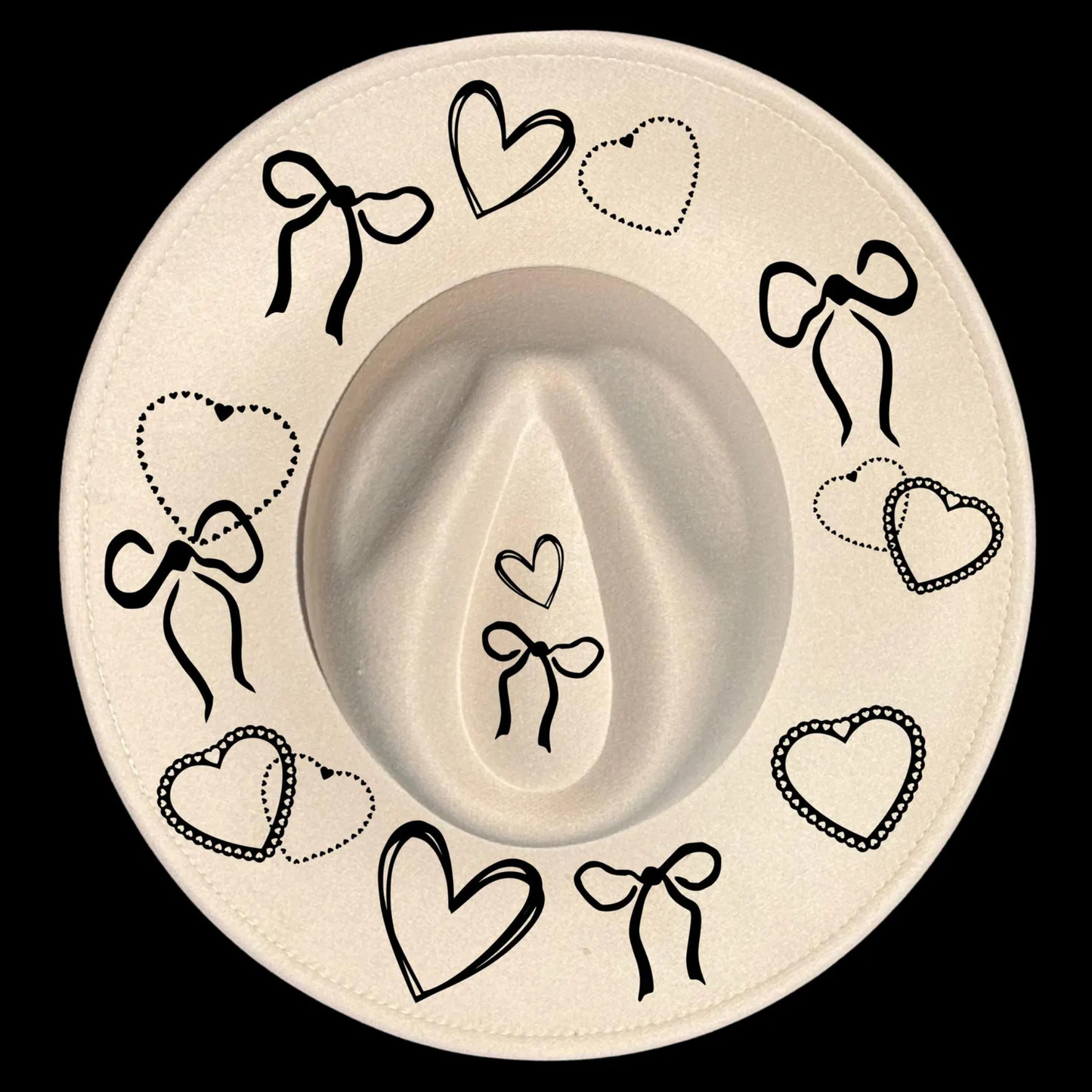 A wide brim cowboy hat with black decorative bows and hearts on a black background