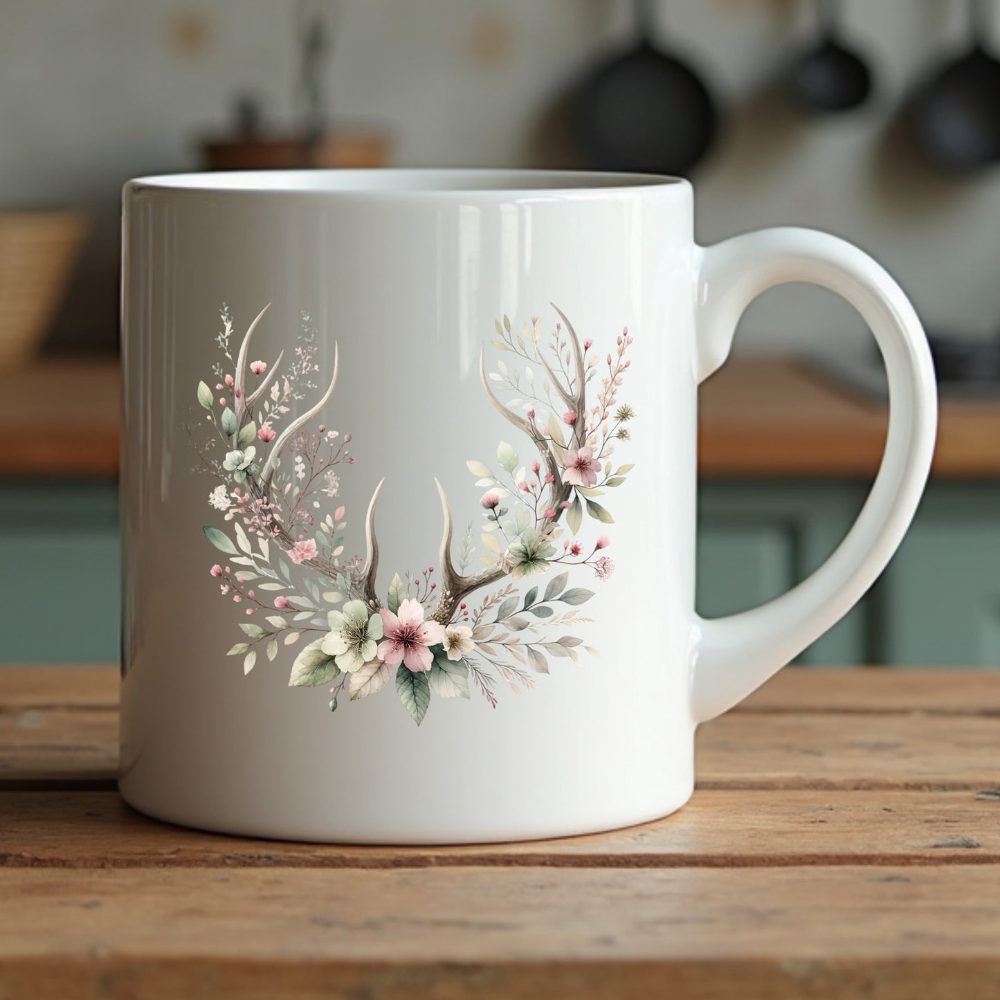 White mug with floral and antler design on a wooden surface
