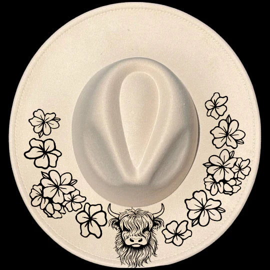White hat with black floral patterns and a highland cow design on a black background
